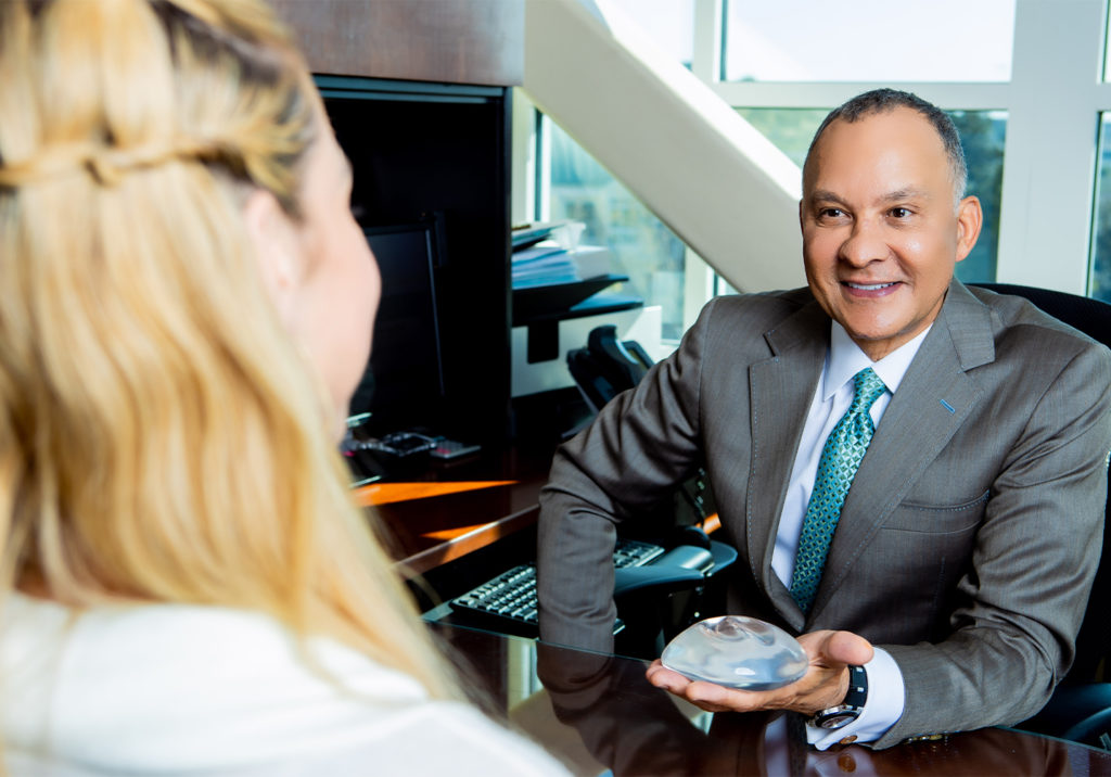 Dr. Delgado explaining the various types of breast implants to a patient.
